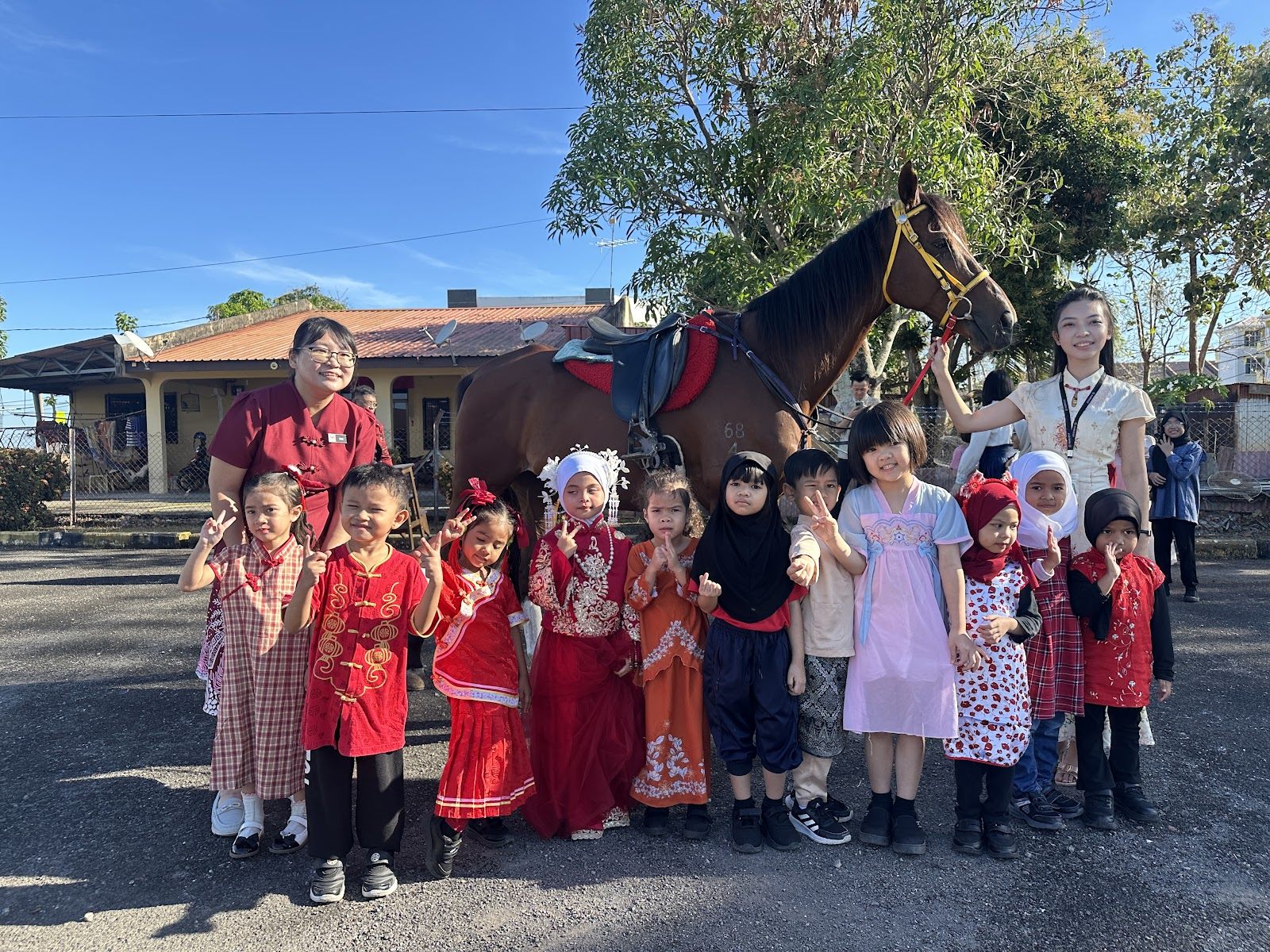 Children in festive outfits posing with a horse and teachers