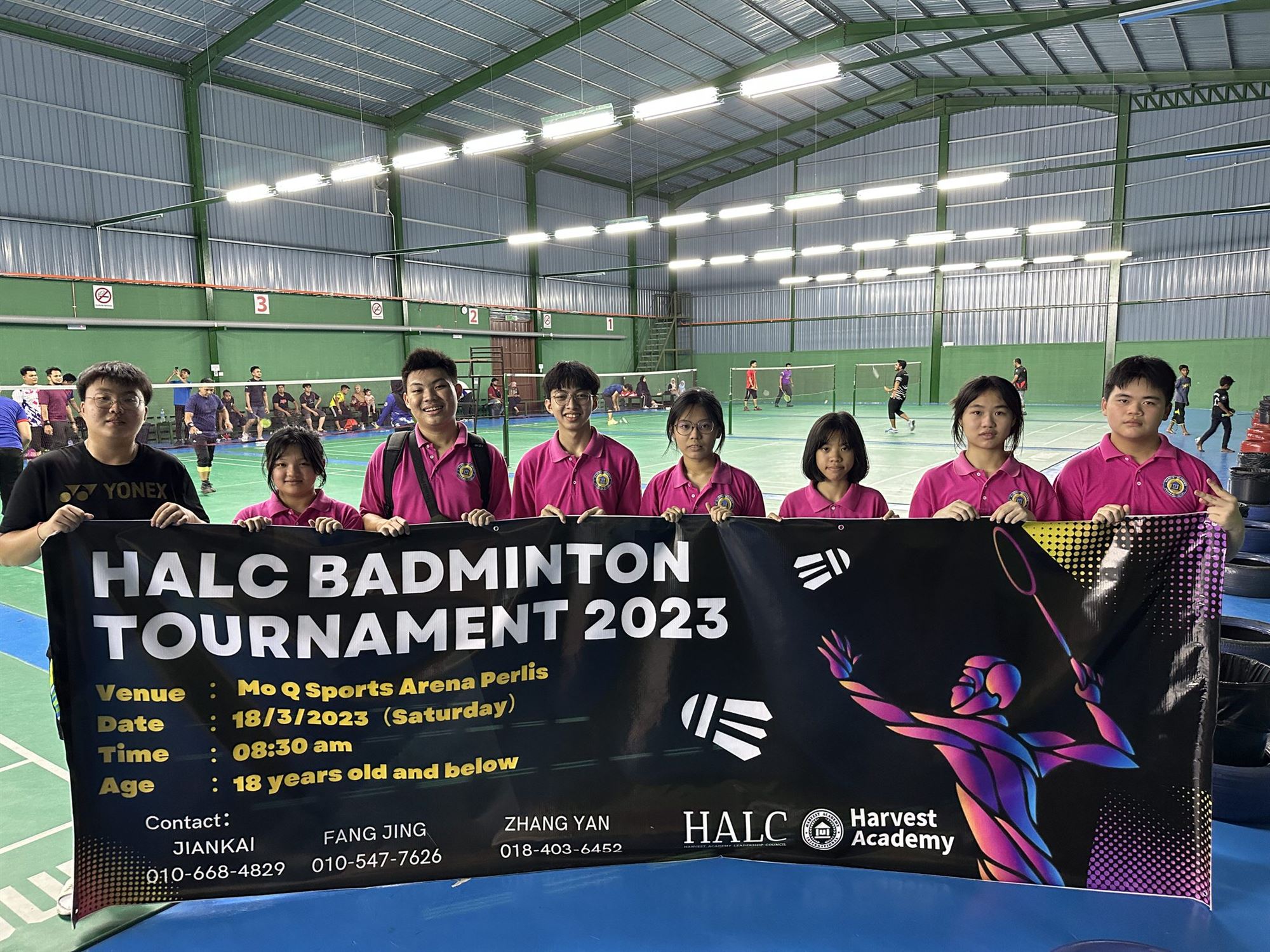 Participants with the HALC Badminton Tournament 2023 banner at the sports arena